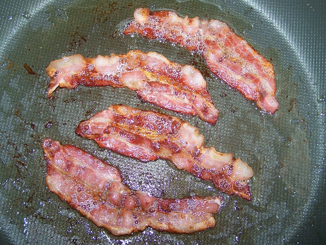 Slices of bacon frying in a pan