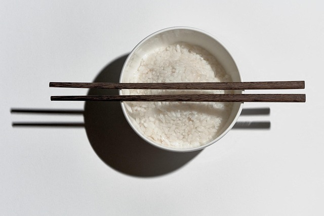 A bowl of white rice with wooden chopsticks placed on top